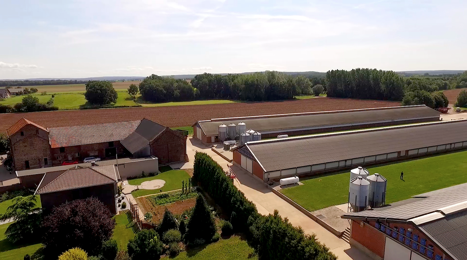 Ein Geflügelhof aus der Vogelperspektive – zu sehen sind drei Putenställe, ein Wohnhaus, ein kleiner Garten und Silos mit Putenfutter. 